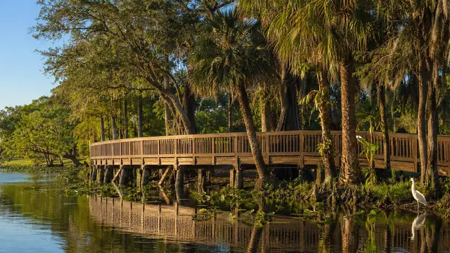 A boardwalk across a park lake in the late-afternoon sun.